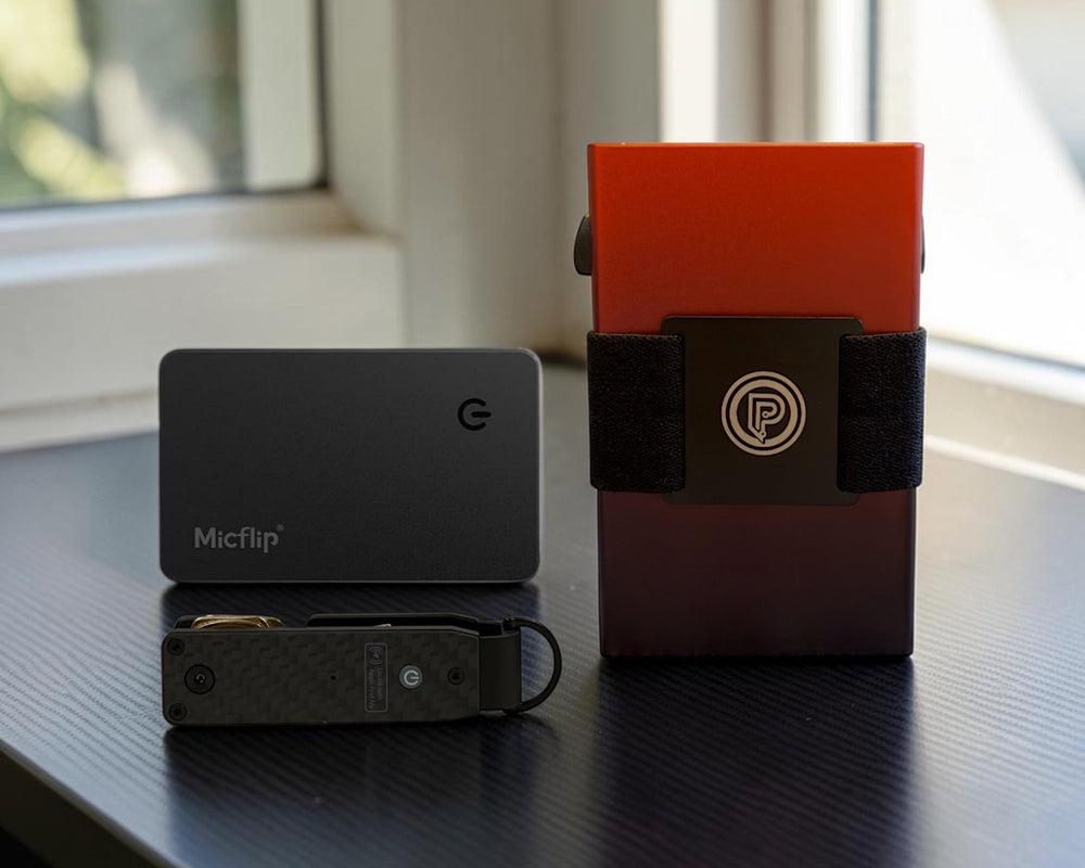 PoofTech Slim RFID Wallet in Ember, Micflip card finder, and key organizer on a dark desk surface.