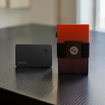 PoofTech Slim RFID Wallet in Ember next to black Micflip wallet card finder on a dark reflective surface.